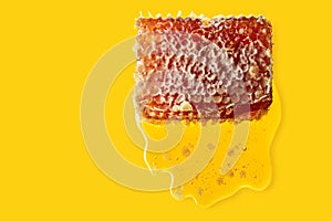 Honeycomb and flowing honey on a yellow background