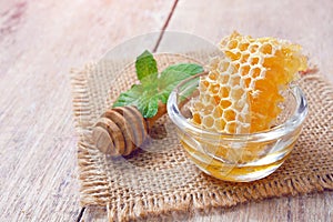 Honeycomb in glass bowl with a wooden honey dipper.