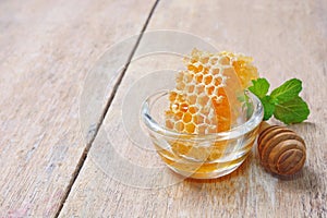 Honeycomb in glass bowl with a wooden honey dipper.