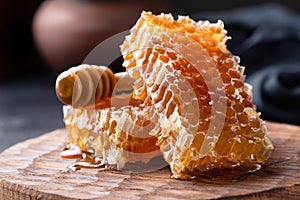 Honeycomb and honey dipper on wooden board