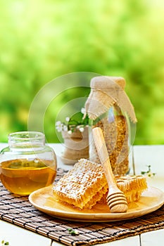 Honeycomb with jar and bee pollen on white wooden background