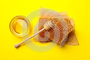 Honeycomb pieces, bowl honey and dipper on yellow background