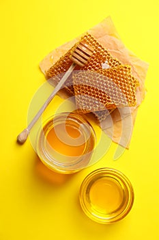 Honeycomb pieces, bowls honey and dipper on yellow background