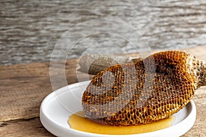 Honeycomb pieces close-up on the white plate with fresh liquid honey golden color beautiful from a bee hive. Food and healthy