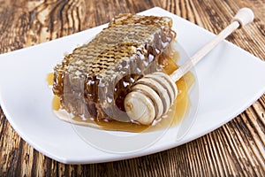 Honeycomb and stick to honey on wooden background