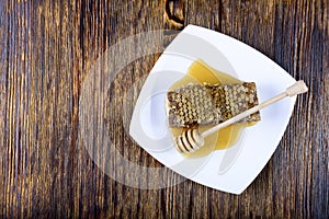 Honeycomb and stick to honey on wooden background