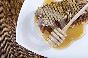 Honeycomb and stick to honey on wooden background