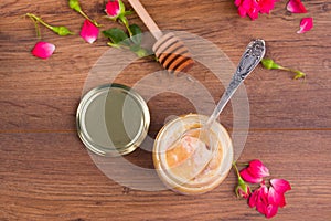 Honeycomb with wooden dipper and fresh blossom, jar with honey and plate with vintage spoons on dark rustic background