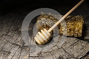 Honeycombs and stick to honey on wooden background