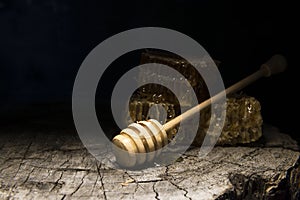 Honeycombs and stick to honey on wooden background