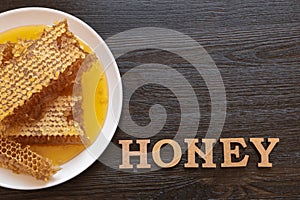 Honeycombs in white plate on the wooden table. Natural organic bee product. Healthy lifestyle. Word honey. Copy space for your