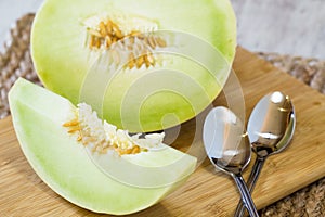 Honeydew Melon Slice With Spoons On Cutting Board