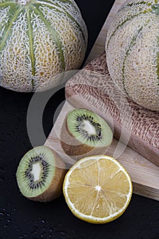 Honeydew melons, a lemon half, green and yellow chopped kiwis