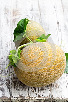 Honeydew melons with sprig on white wooden table