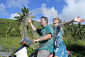 Honeymoon couple riding a motor scooter in a tropical pacific is