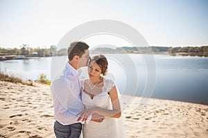 Honeymoon of just married wedding couple. happy bride, groom standing on beach, kissing, smiling, laughing, having fun on beach