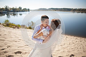 Honeymoon of just married wedding couple. happy bride, groom standing on beach, kissing, smiling, laughing, having fun on beach