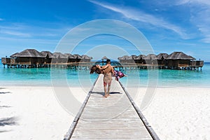 Honeymoon on Maldives. Man holding his wife on arms on bridge on ocean beach