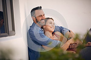 Honeymoon phase vibes. an affectionate mature man embracing his wife while sitting outdoors.