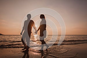 honeymoon, silhouette of couple walking on the beach at sunset