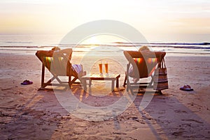 Honeymoon travel, silhouettes of happy couple relaxing in deck chairs on the beach