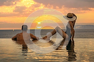 Honeymoon vacation - couple enjoying romantic sunset in infinity pool at luxury resort