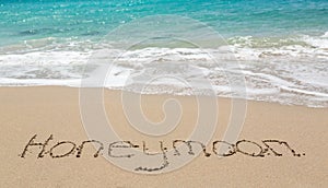 Honeymoon written in sand with sea surf