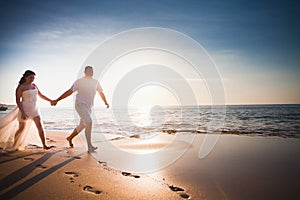 Honeymooners couple just married running at beach