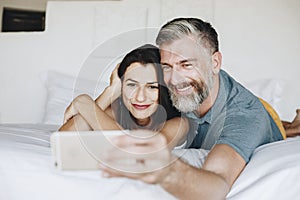 Honeymooners taking a selfie in bed