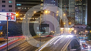 Hong Kong Business District timelapse at Night. Corporate building at the back and busy traffic across the main road at