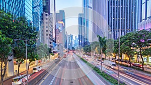 Hong Kong street with busy traffic and skyscraper office at dusk day to night timelapse.