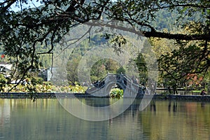 Hongcun Ancient Town in Anhui Province, China. The stone bridge crossing Nanhu Lake with foreground branches