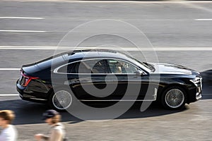 Hongqi H9 at the city road in motion. Black full-size luxury car driving along the street in city, side view. Accelerating with