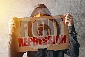 Hooded activist protestor holding Fight repression protest sign photo