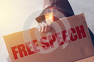 Hooded activist protestor holding Free Speech protest sign