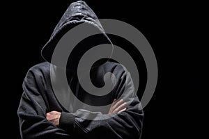Hooded anonymous hacker with arms crossed, isolated on black background