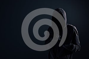 Hooded computer hacker with obscured face using digital tablet