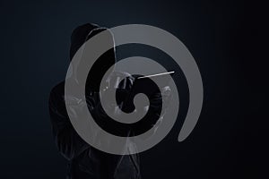 Hooded computer hacker with obscured face using digital tablet photo