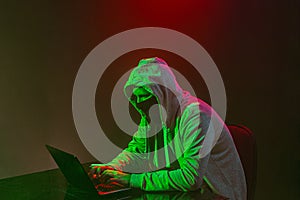 Hooded computer hacker stealing information with laptop