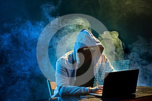 Hooded computer hacker stealing information with laptop