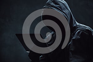 Hooded computer hacker using digital tablet