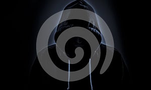 Hooded hacker in dark photo
