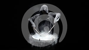 Hooded man beats drum with flour