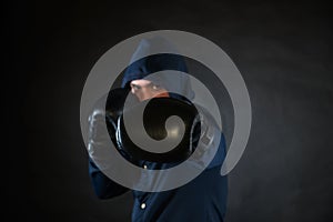 Hooded man in a fighting stance with black boxer gloves.