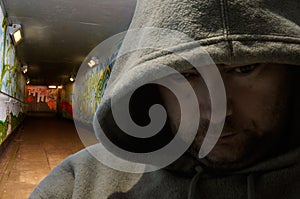 Hooded man in graffiti-decorated subway