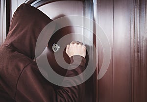 Hooded man knocking on door photo