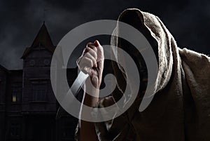 Hooded man in mask with a knife