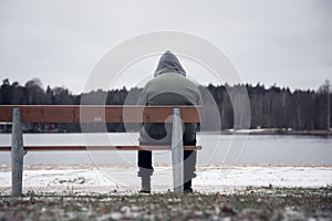 Hooded man sitting alone on park bench