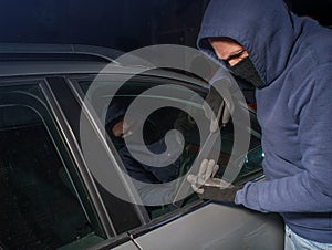 Hooded thief looking to break into a car photo