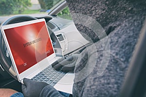 Hooded thief tries to break the car`s security systems with laptop